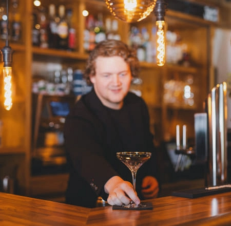 Bartender serviert Cocktail an Holztheke