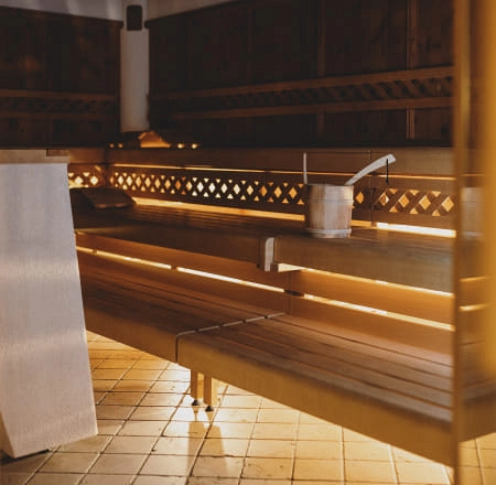 Innenansicht einer Sauna mit Holzbank und Eimer.