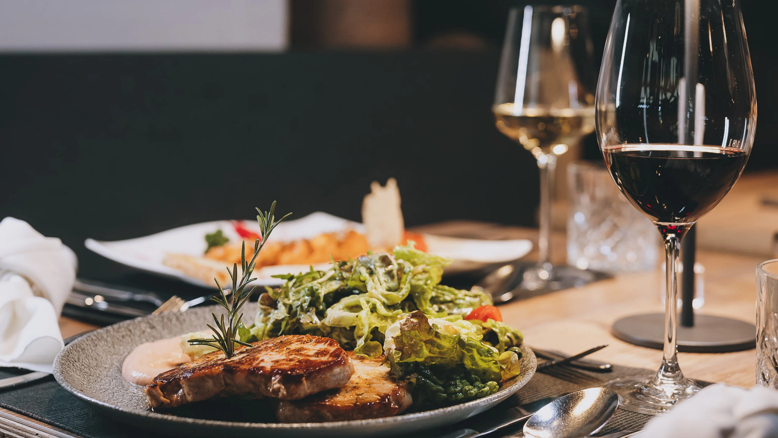 Teller mit Fleisch und Salat, Gläser mit Wein auf dem Tisch