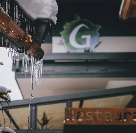 Eiszapfen an einem Dach mit Restaurant-Schild im Hintergrund