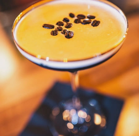 Cocktail mit Kaffeebohnen, serviert in einer eleganten Glaskaraffe