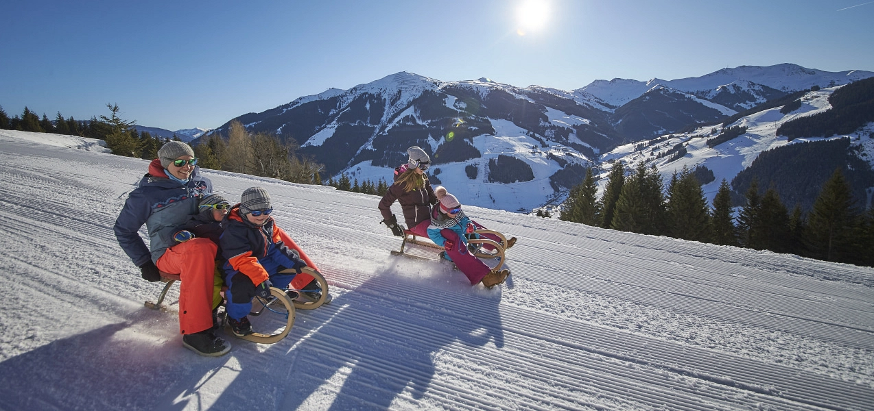 Family tobogganing in the Alps on snow