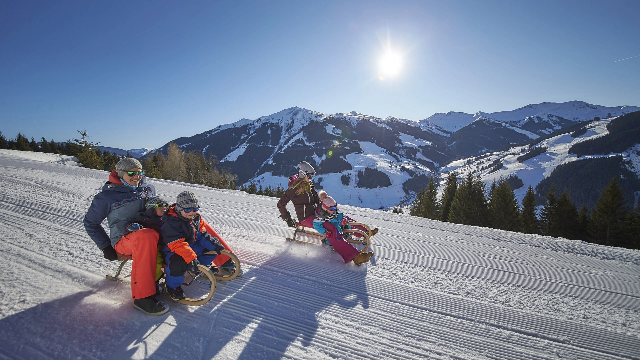 Familie rodeln im Schnee mit Bergen im Hintergrund