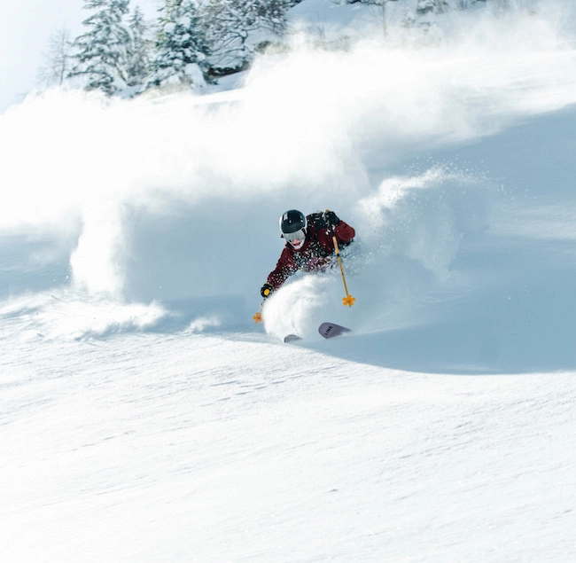 Skifahrer carving durch frischen Schnee in einer verschneiten Landschaft